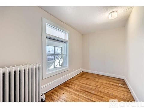 A room with wooden floors and a window overlooking a street.