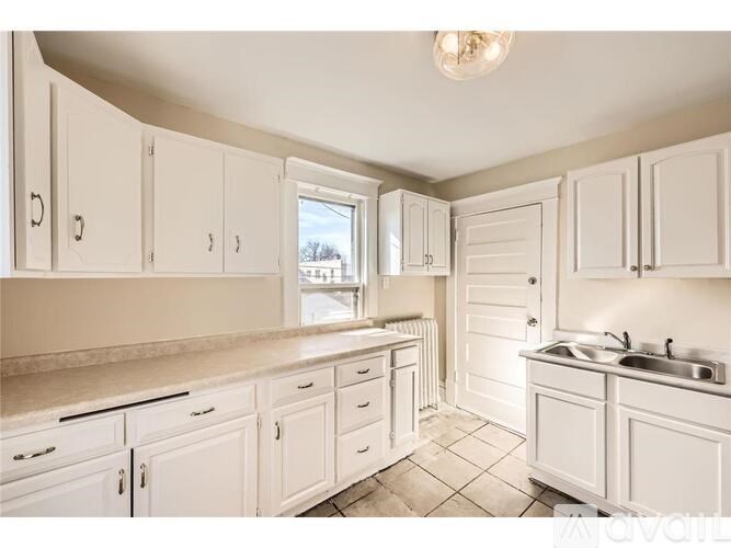 A kitchen with white cabinets and a window.