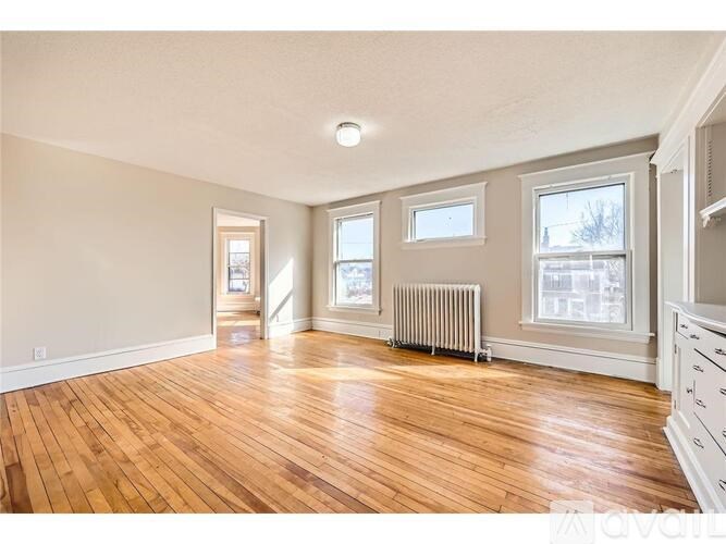 A spacious room with wooden floors and white walls.