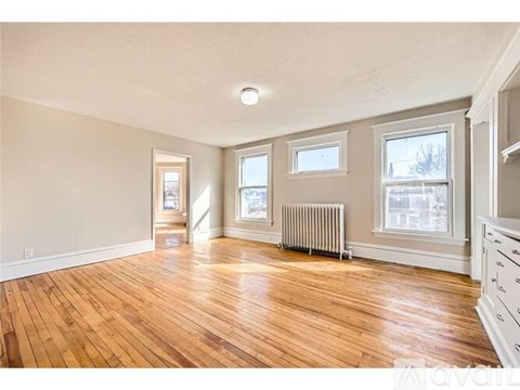 A spacious room with wooden floors and white walls.