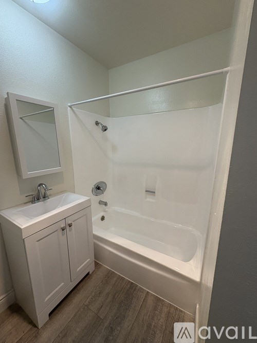 A white bathroom with a sink, mirror, and bathtub.