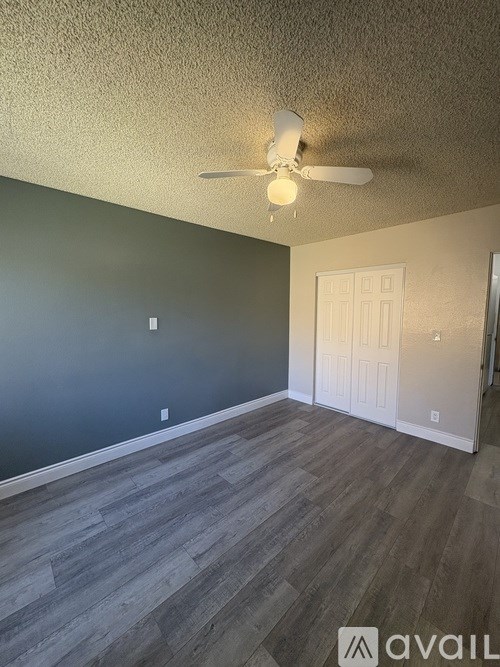 A room with a ceiling fan and a door.
