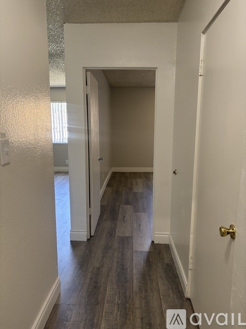 A hallway with a door on the right and a light switch on the wall.