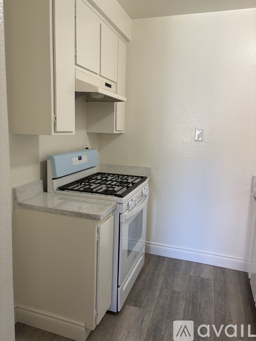 A small kitchen with a stove and a wall socket.