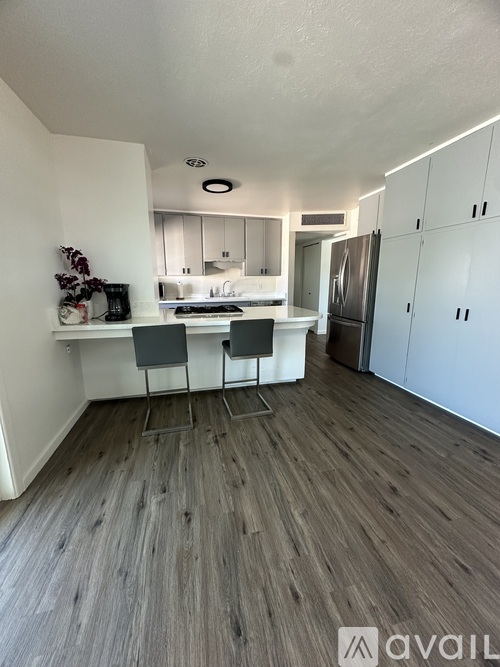A kitchen with a refrigerator, sink, and cabinets.