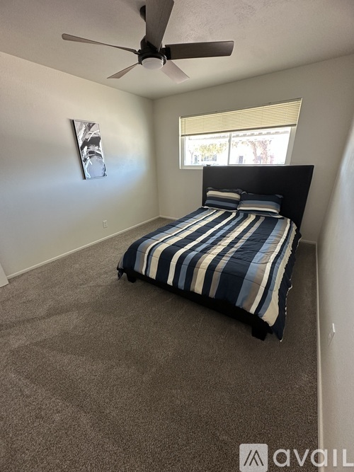A bedroom with a bed, carpet, and a ceiling fan.