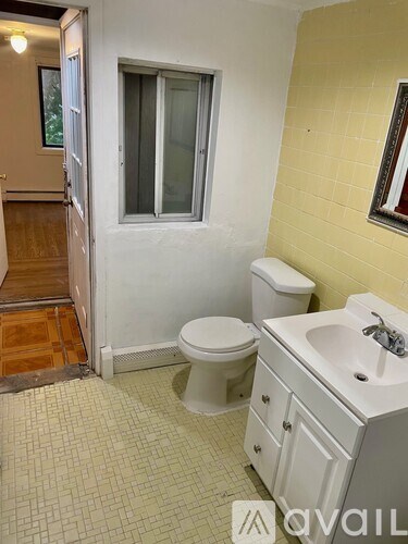 A bathroom with a toilet, sink, and a window.