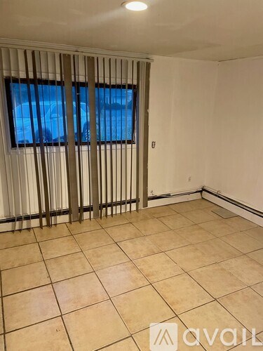 A room with a window covered by vertical blinds.