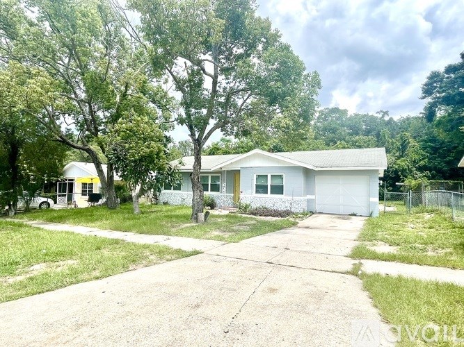 A house with a white garage door is surrounded by trees.