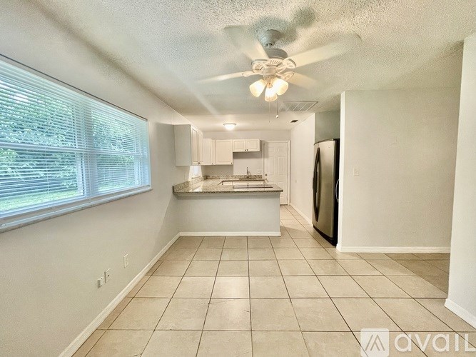 A kitchen with a refrigerator, sink, and a window with blinds.