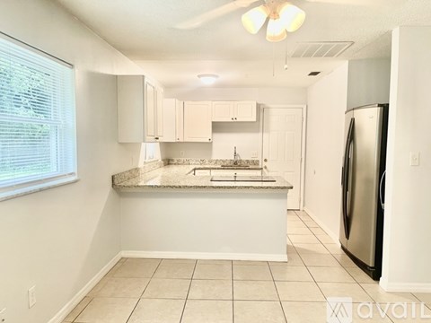 A kitchen with white cabinets and a black refrigerator.