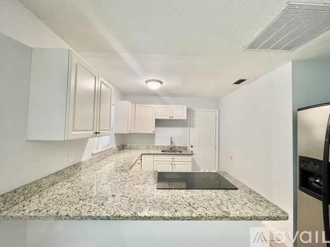 A kitchen with granite countertops and white cabinets.