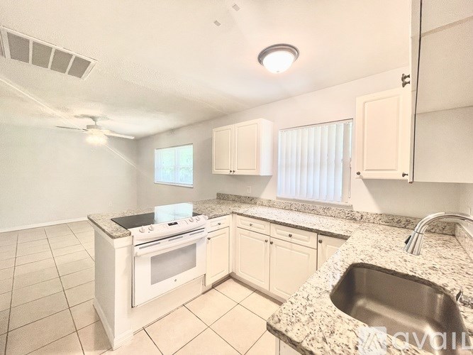 A kitchen with a white stove top oven and a granite counter top.