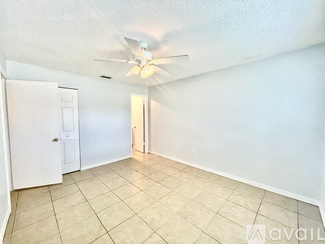 A room with a ceiling fan and tile flooring.