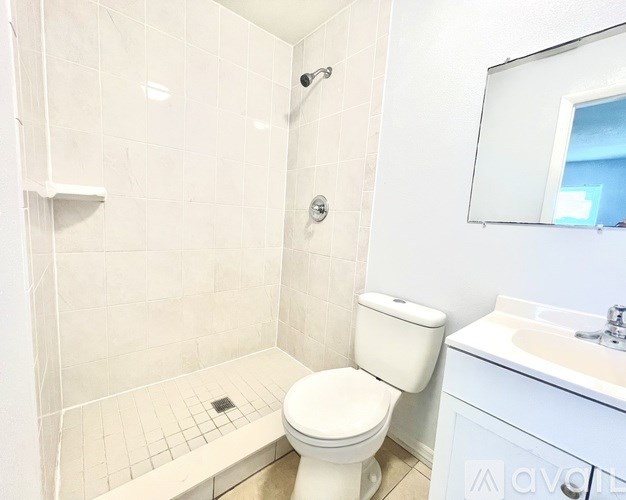 A white toilet in a bathroom with a white tiled shower area.