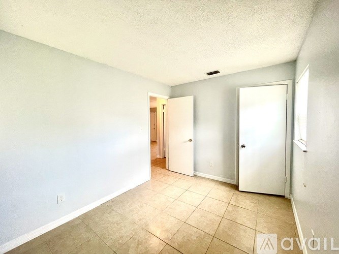 A room with white walls and a tiled floor with two doors.