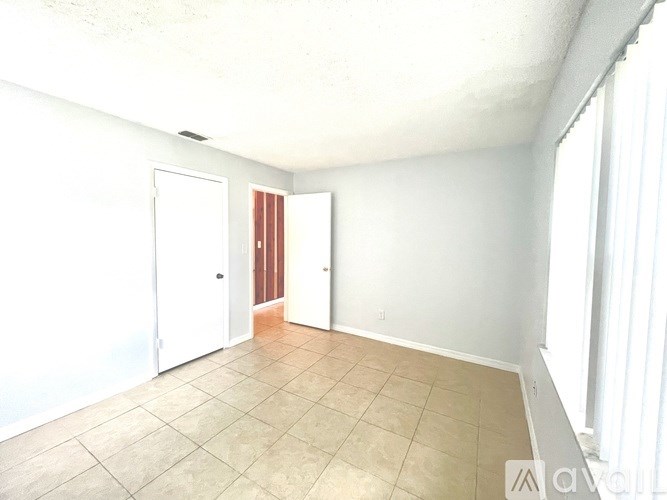 A room with a white door and a window with blinds.