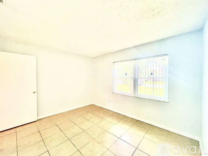 A room with a tiled floor and a window with blinds.