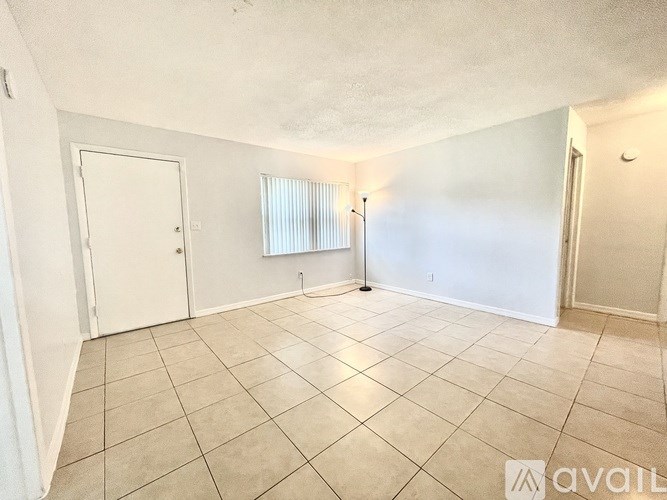 A room with white walls and a tiled floor with a door and a window.