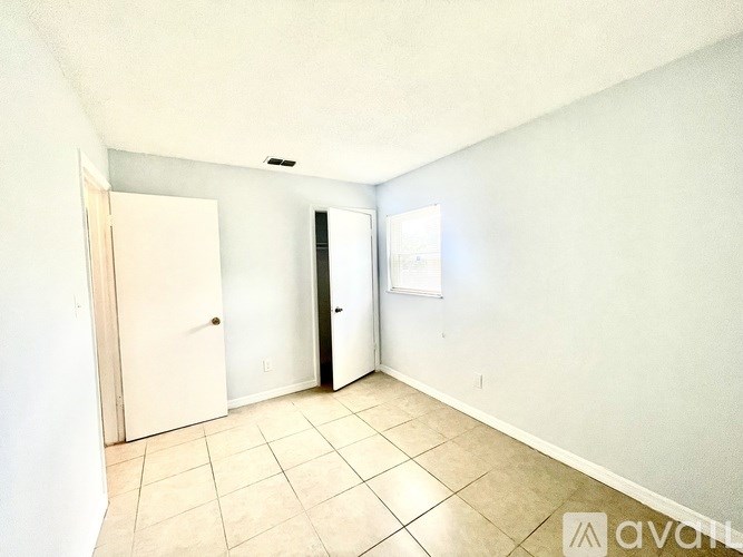 A room with a white door, a white wall, and a white ceiling.