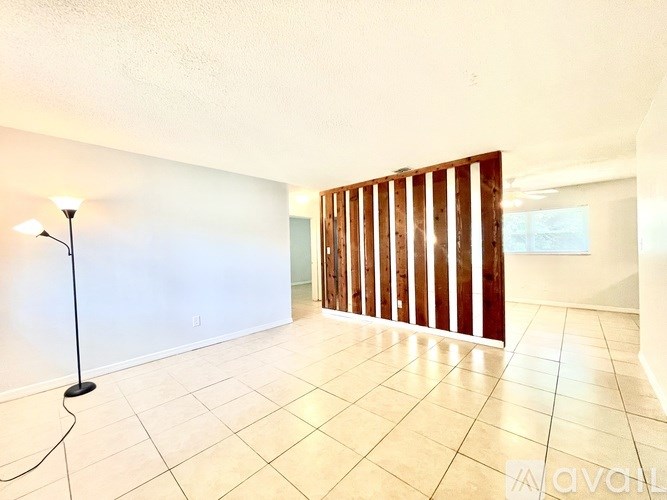 A room with a lamp on the floor and a white wall.