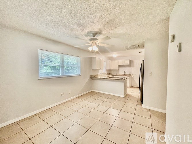 A room with a ceiling fan and tiled flooring.