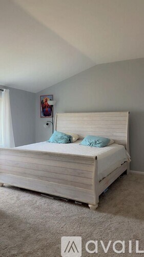 A bed with a wooden headboard and two blue pillows is in the image.