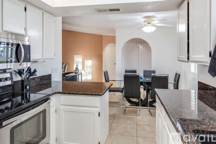 A kitchen with white cabinets and a black countertop.