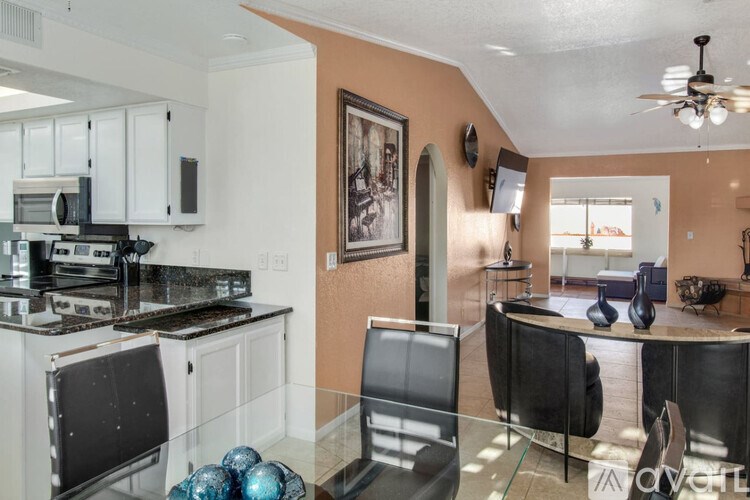 A kitchen with a black chair and a glass table.