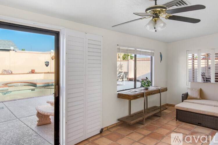 A room with a ceiling fan and a table with a plant on it.