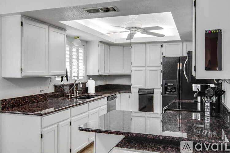 A kitchen with white cabinets and a black granite countertop.