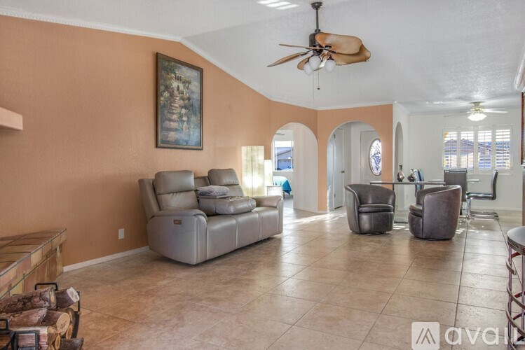 A living room with a ceiling fan and a painting on the wall.