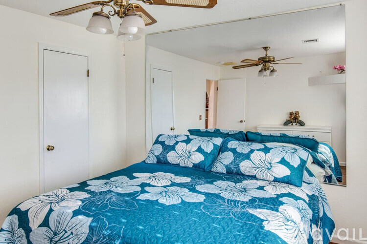 A bedroom with a bed covered in a blue and white floral comforter.