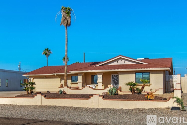 A house with a red roof and a palm tree in front.