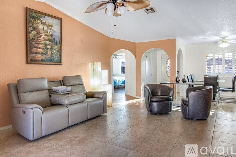 A living room with a painting on the wall and a fan on the ceiling.