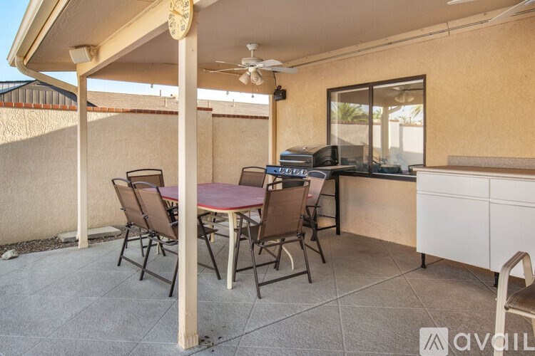 A patio with a table, chairs, and a ceiling fan.