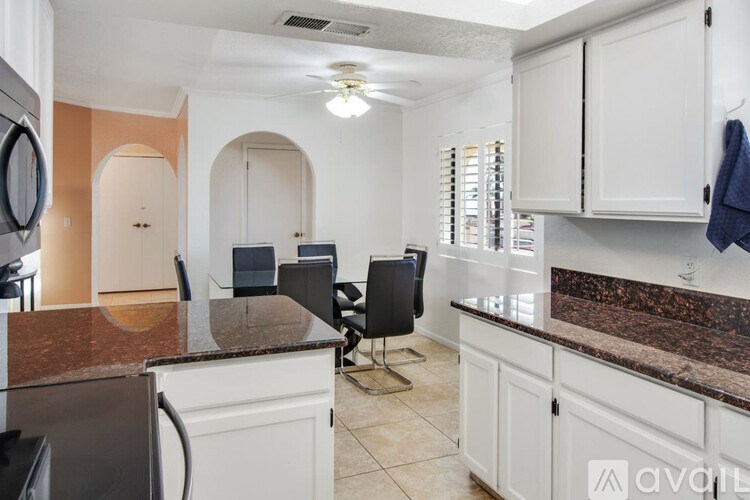 A kitchen with white cabinets and a black countertop.