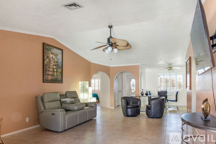 A living room with a grey sofa and a ceiling fan.