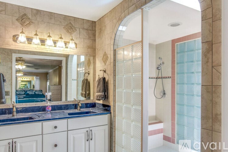 A bathroom with a blue counter top and a shower with a glass door.