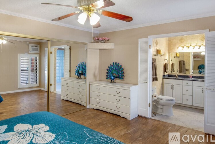 A bedroom with a ceiling fan and a bathroom visible through the open door.