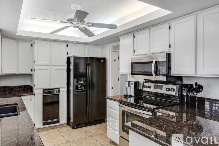 A kitchen with black appliances and white cabinets.