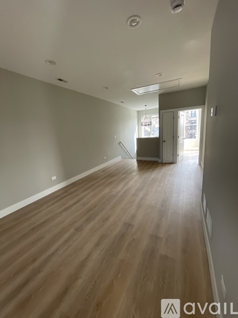 A spacious room with wooden flooring and a staircase in the background.