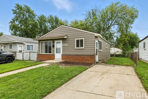 A house with a grey siding and a brown roof is for sale.