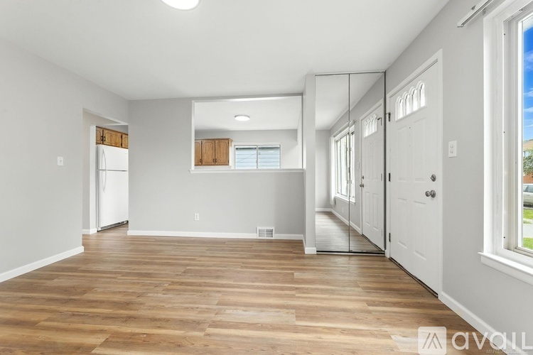 A spacious room with wooden flooring and white walls.