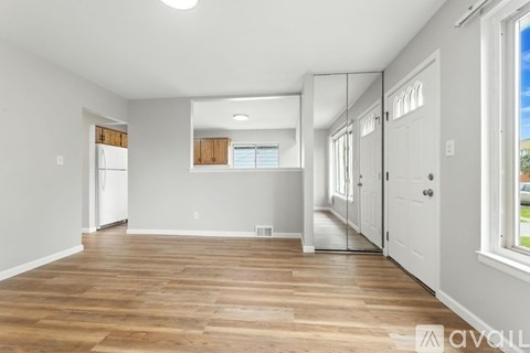 A spacious room with wooden flooring and white walls.