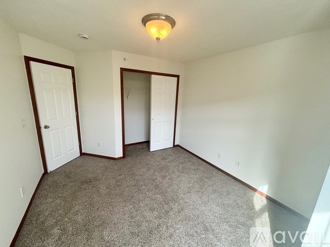 A room with carpeted floor and two doors.