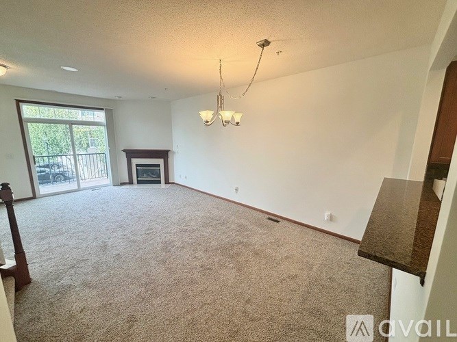 A living room with a carpeted floor and a fireplace.