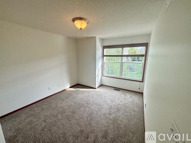 A carpeted room with a window and a ceiling light.