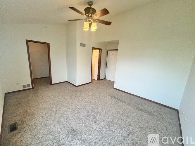 A room with a ceiling fan and carpeted floor.
