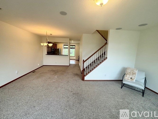 A spacious living room with a carpeted floor and a staircase leading to the upper level.